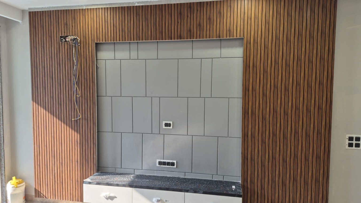 Wood-tone slatted feature wall and inset panels at C1, Palam Vihar — work ongoing